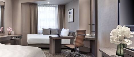 Une chambre d’hôtel comprenant un lit, un bureau avec une chaise, une télévision et une salle de bain.