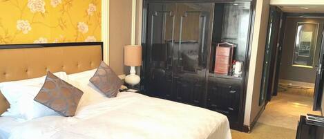 A hotel room with a bed, a wardrobe, a lamp, and a television.