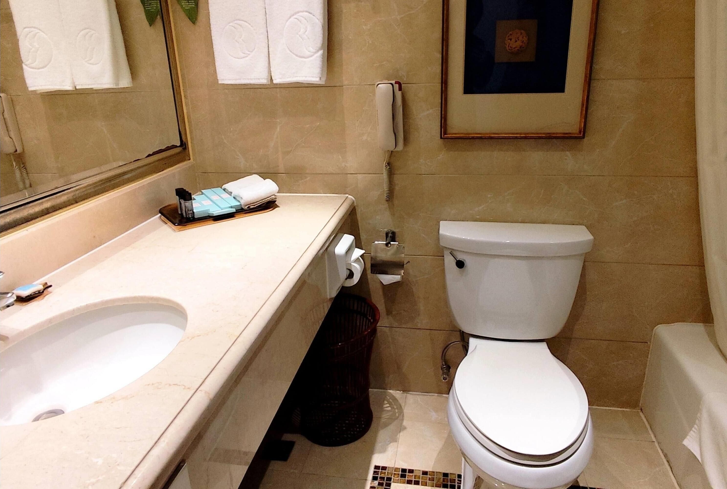 A bathroom with a sink, toilet, and a framed picture on the wall.