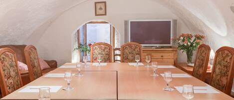 An arched room with a wooden dining table set for six, surrounded by floral upholstered chairs.