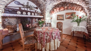A rustic dining area with a stone fireplace, wooden furniture, and a table set for two.