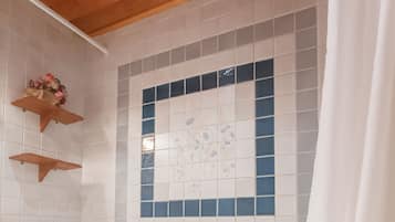 A wooden cabin bathroom with a bathtub, wooden shelves, and a tiled wall with a decorative pattern.