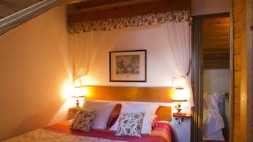 Ein Schlafzimmer mit einem Bett, zwei Nachttischlampen, einem gerahmten Bild an der Wand und einer Holztür.