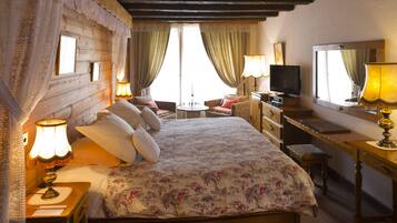 A cozy hotel room with a wooden bed, a desk with a television, and a comfortable seating area.