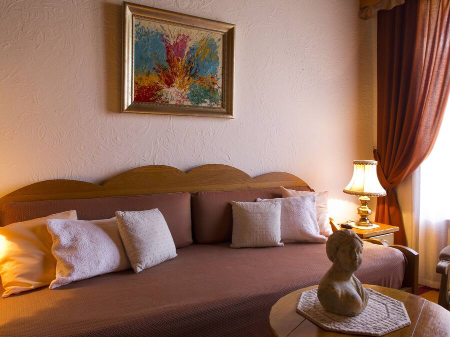 Une chambre d’hôtel avec un lit, une lampe, une chaise et un tableau au mur.
