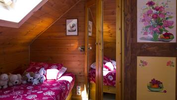 A cozy wooden cabin bedroom with two beds, a skylight, and artwork on the walls.