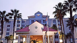 A hotel with a prominent entrance, a flag, and palm trees. - SpringHill Suites by Marriott Orlando Lake Buena Vista South (Kissimmee)
