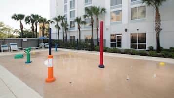 A water play area with colorful play structures and a building in the background.