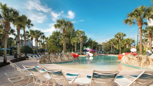 A pool area with lounge chairs and palm trees. - SpringHill Suites by Marriott Orlando Lake Buena Vista South (Kissimmee)