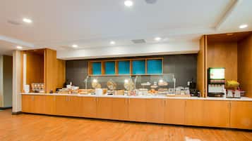 A modern breakfast bar with wooden cabinets, a glass display case, and a variety of breakfast items.
