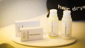 A bathroom counter with three Paul Mitchell hair care products and a white box.