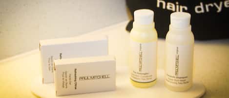Una encimera de baño con tres productos para el cabello Paul Mitchell y una caja blanca.