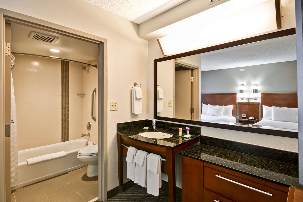 A bathroom with a bathtub, toilet, sink, and a large mirror.