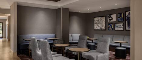 A modern lounge area with seating, tables, and artwork on the walls.