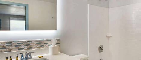 Ein Badezimmer mit Waschbecken, Spiegel und Dusche.
