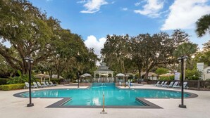 A swimming pool with lounge chairs and umbrellas, surrounded by trees and a gazebo. - Best Western Plus St. Simons (St. Simons Island)