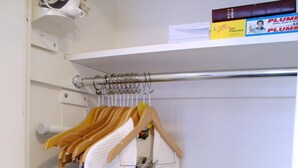 A white robe hanging on a rack in a room with a blue towel, a whiteboard, and a shelf with books and a magazine.