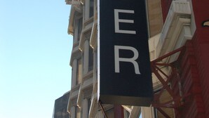 A sign for "The TOSSER" hotel, featuring a classic architectural style with ornate detailing and large windows.