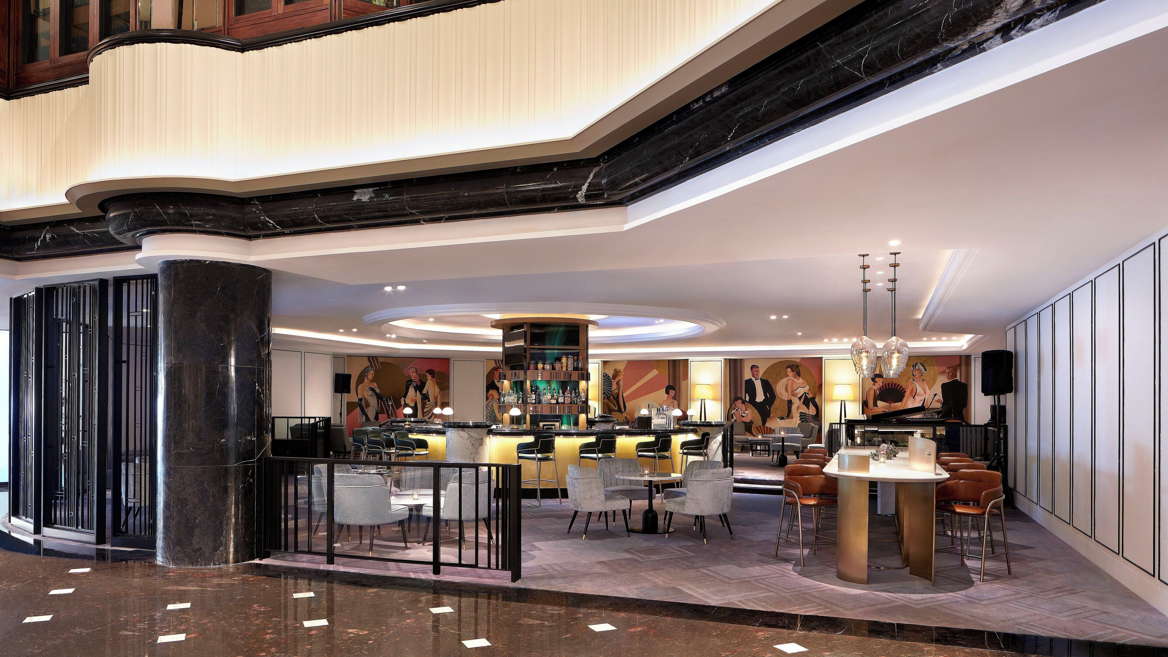 A modern hotel lobby with a bar area, seating arrangements, and a staircase.