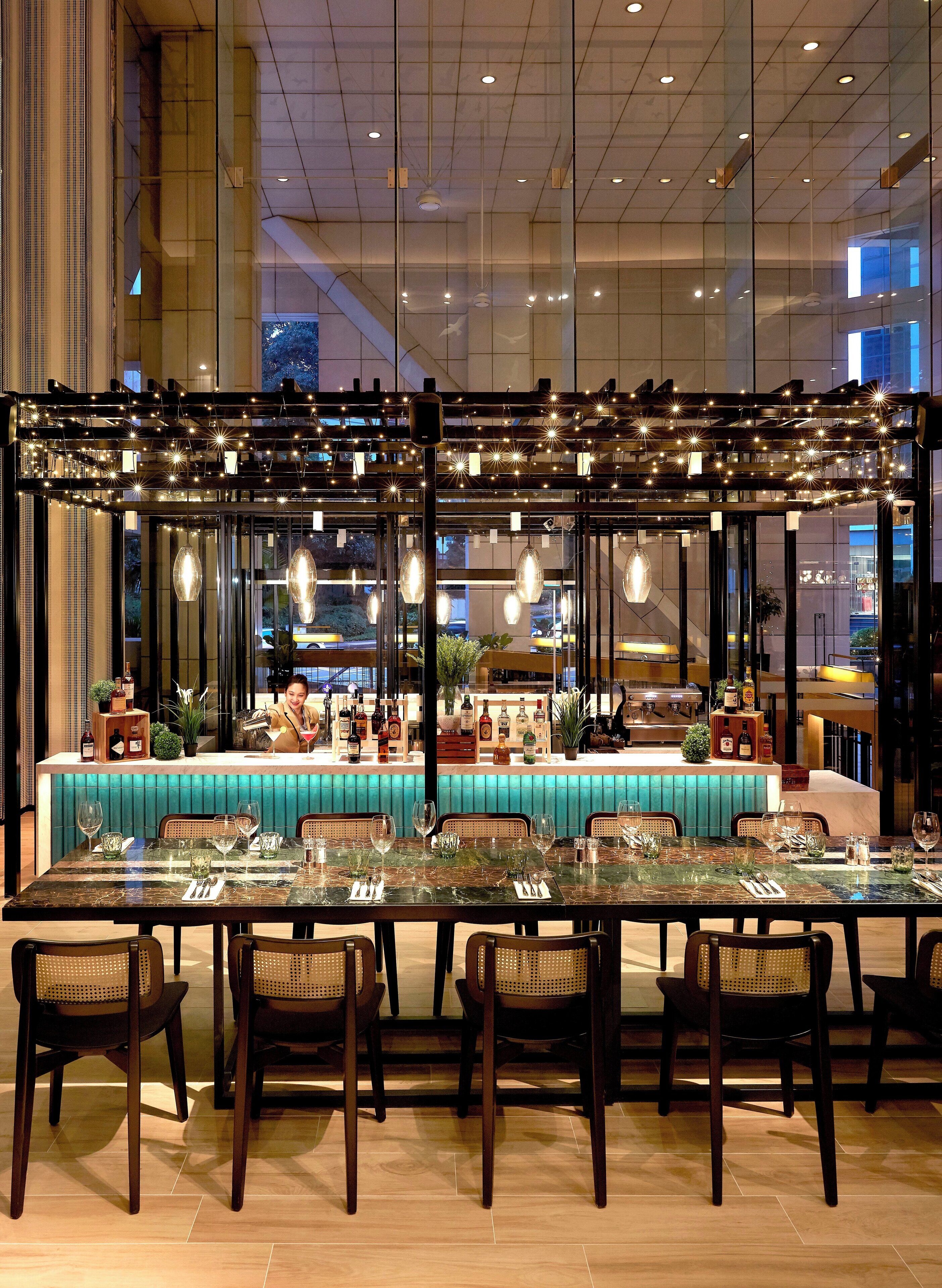 A spacious dining area with a long table, multiple chairs, and a bar counter with various bottles and glasses.