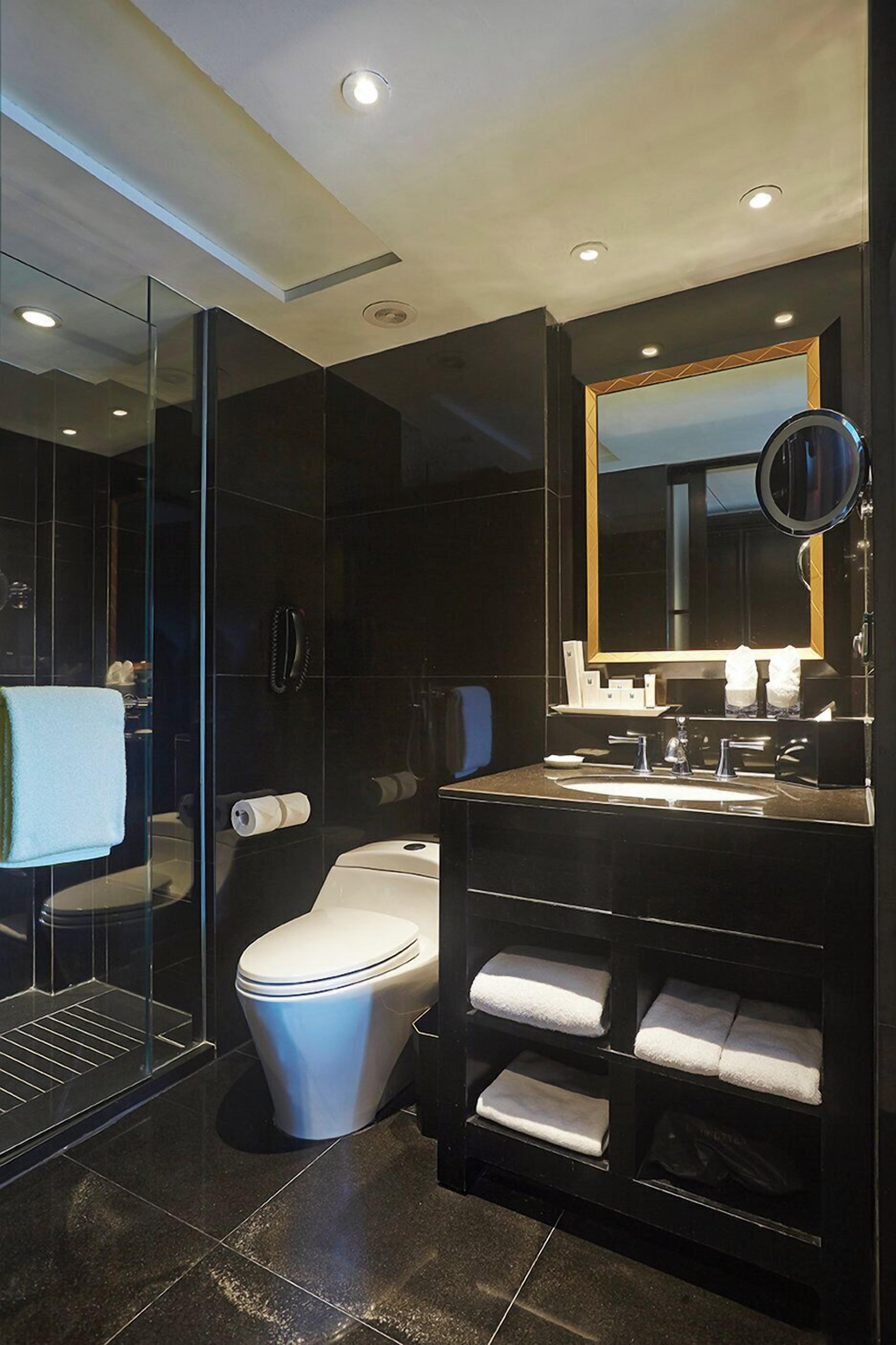 Une salle de bain moderne avec une douche à parois de verre, des toilettes blanches, un meuble-lavabo avec un miroir et un porte-serviettes.