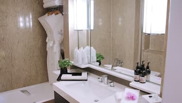 Un baño moderno con un lavamanos grande, una bañera y un espejo. Hay toallas y artículos de aseo en la encimera.