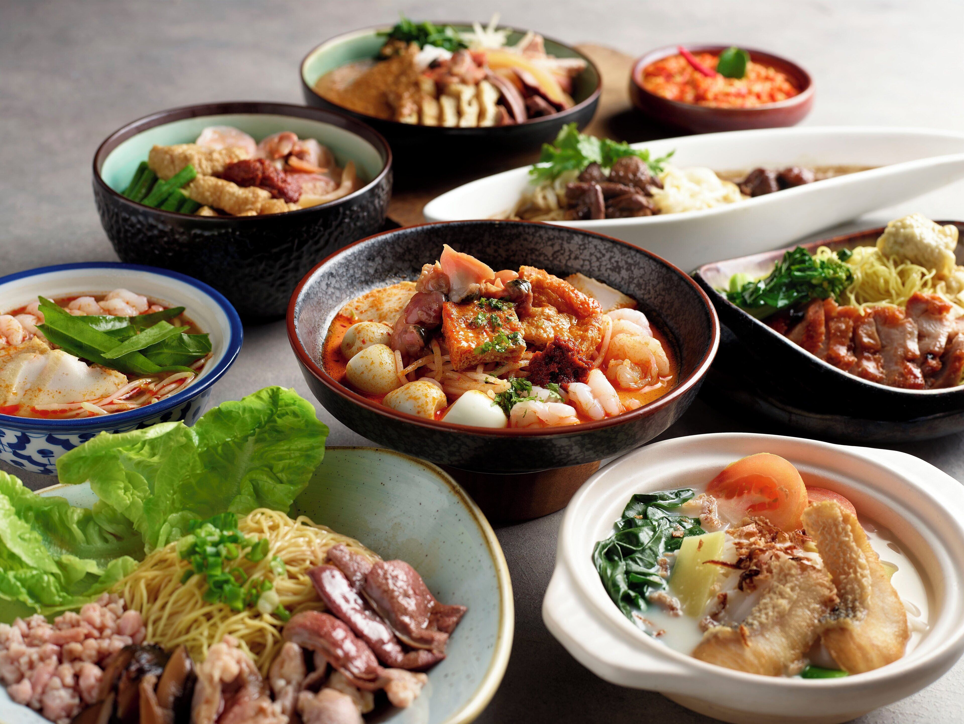 A variety of dishes in bowls, including seafood, noodles, and vegetables.