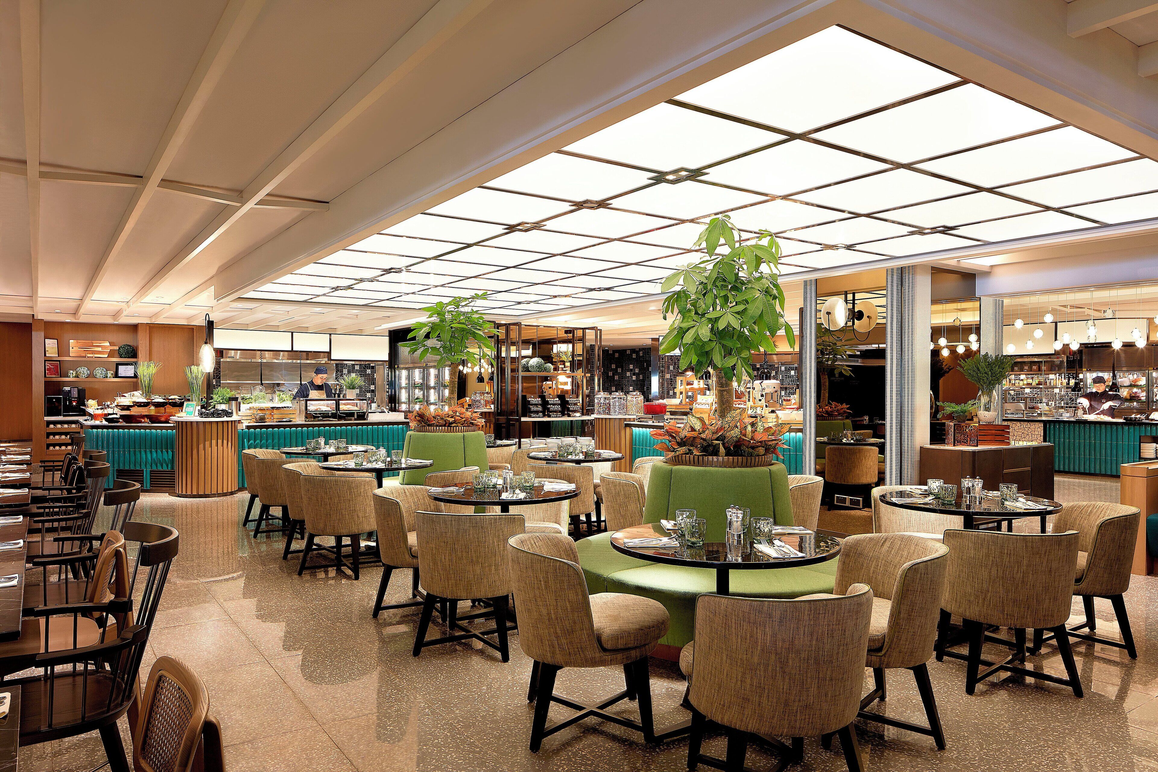 A spacious restaurant with high ceilings, large windows, and a variety of seating arrangements including round tables and booths.