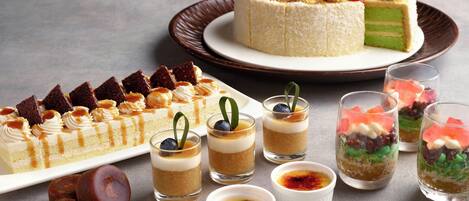 Une table de desserts avec divers gâteaux, pâtisseries et petits desserts servis dans des verrines.