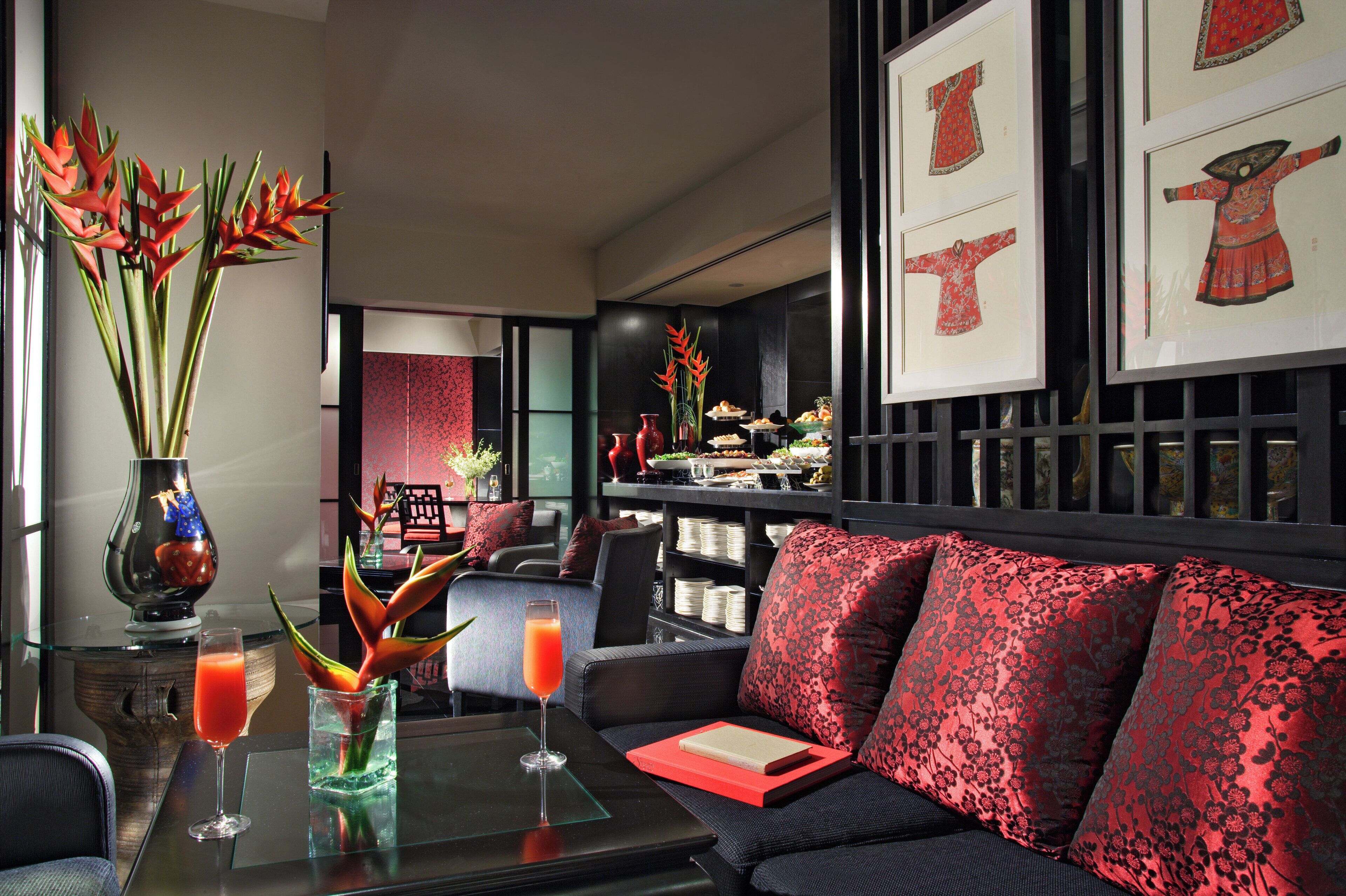 A modern living area with a sofa, a glass table with drinks, and decorative plants.