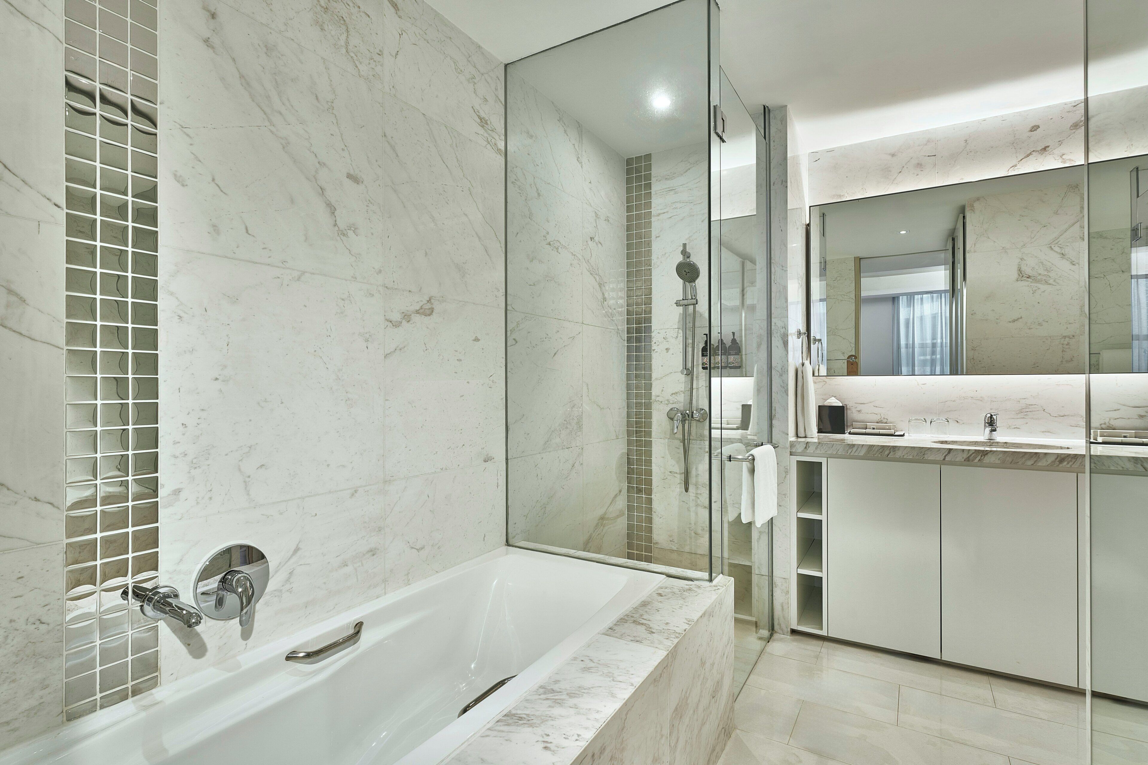 A modern bathroom with a glass-enclosed shower, a freestanding bathtub, and a vanity with a mirror.