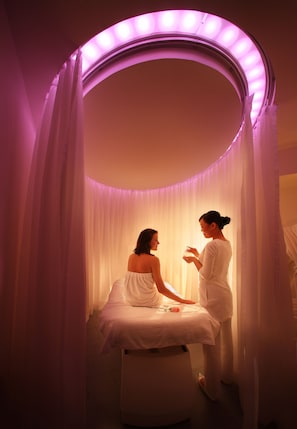Habitación con tocador circular y cama, con iluminación ambiental púrpura.