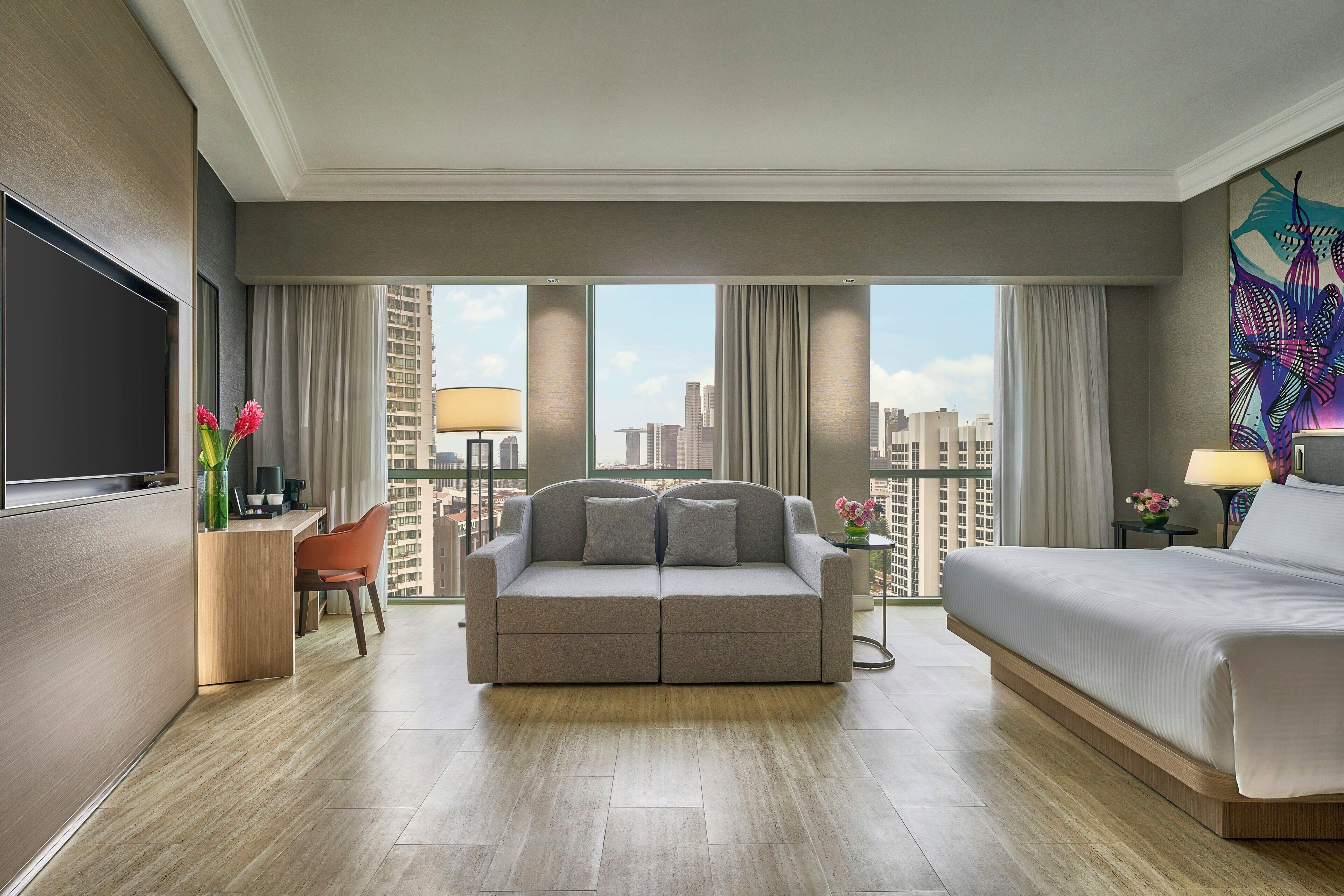 A hotel room with a sofa, a bed, a desk, and a TV.