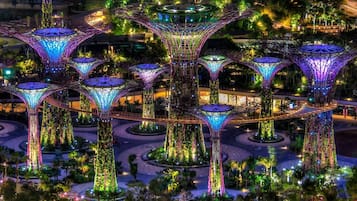 A large, illuminated structure with multiple interconnected towers and a central dome, surrounded by greenery and pathways.