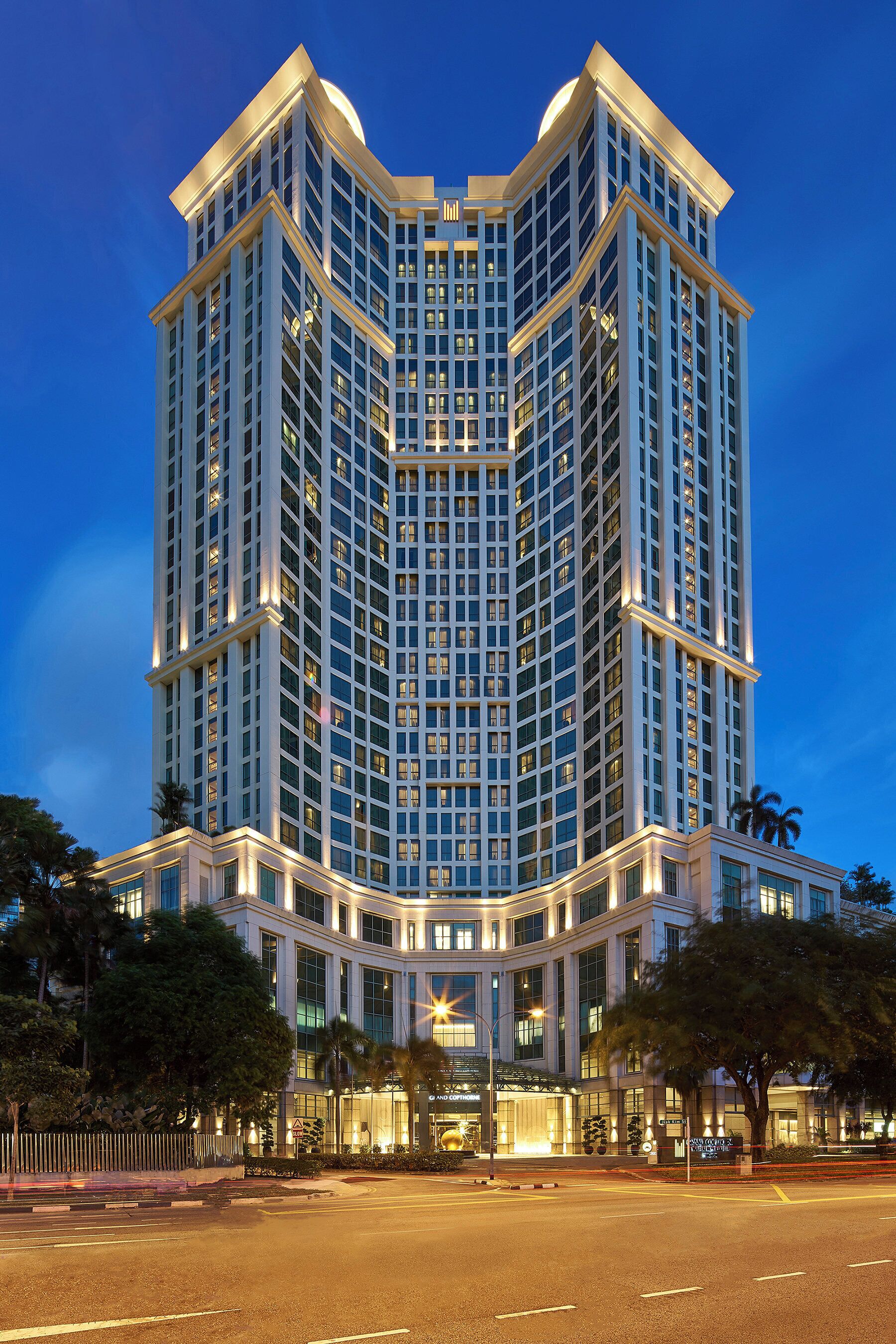 Un hôtel de grande hauteur à l’architecture moderne, caractérisé par une structure imposante en angle et de nombreux balcons.