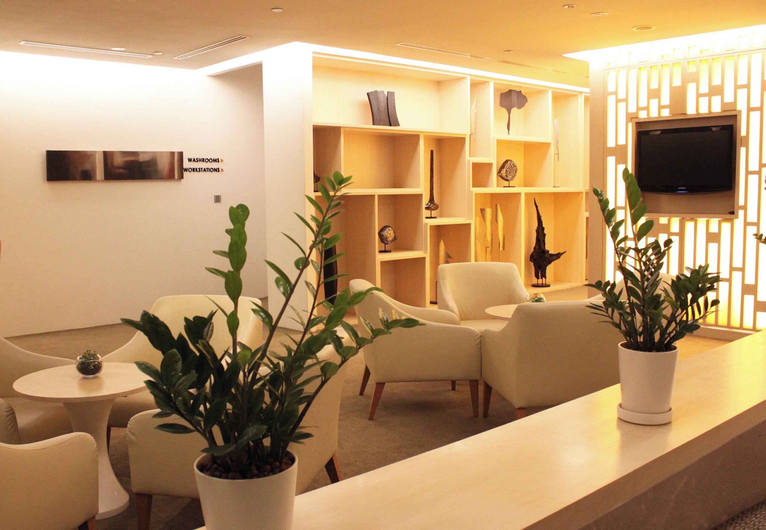 A modern hotel lobby with a reception desk, seating area, and shelves with decorative items.
