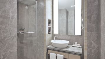 Un baño moderno con ducha acristalada, un espejo grande y un tocador con lavabo y toallero.
