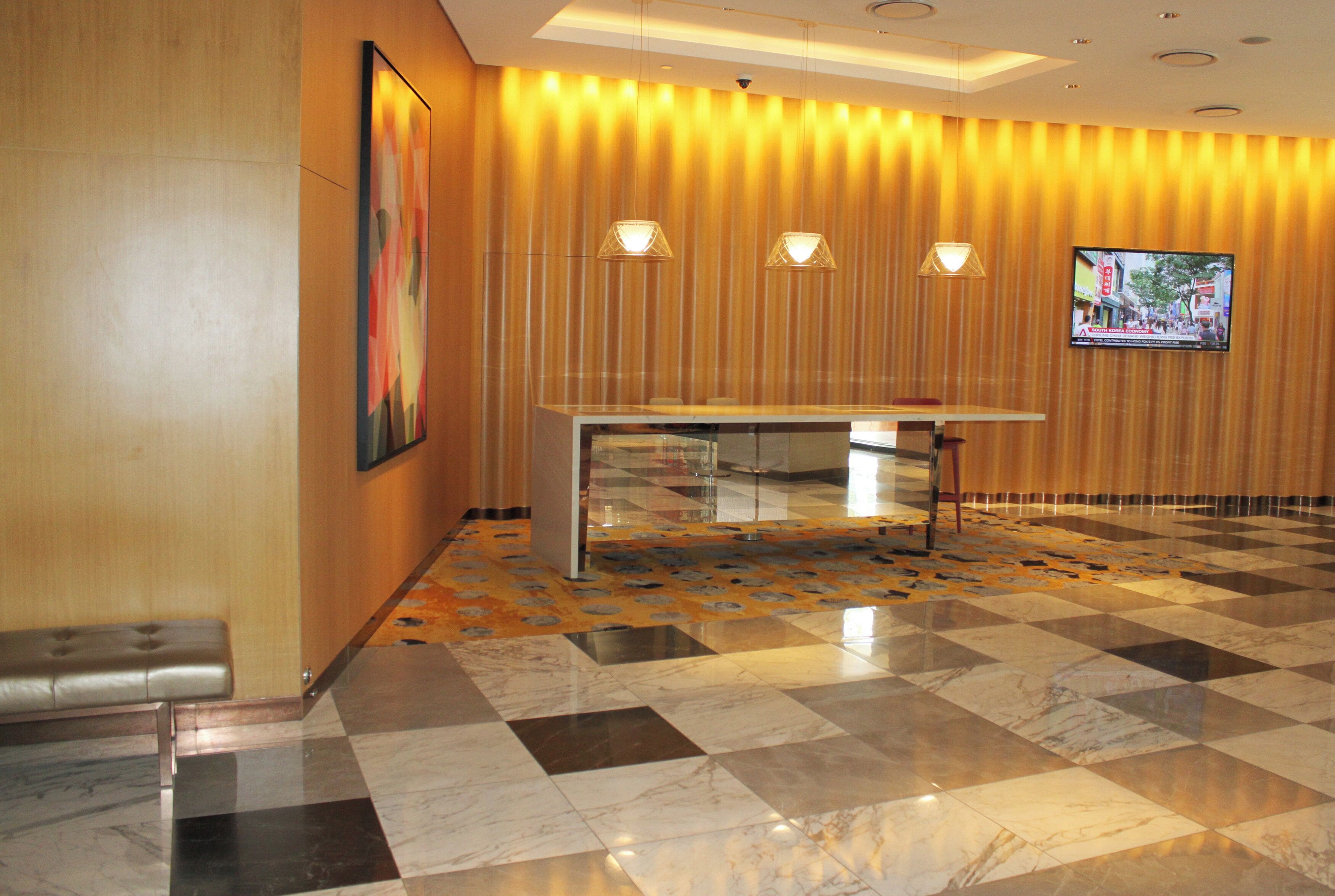 A lobby with a checkered floor, a reception desk, and a television screen on the wall.