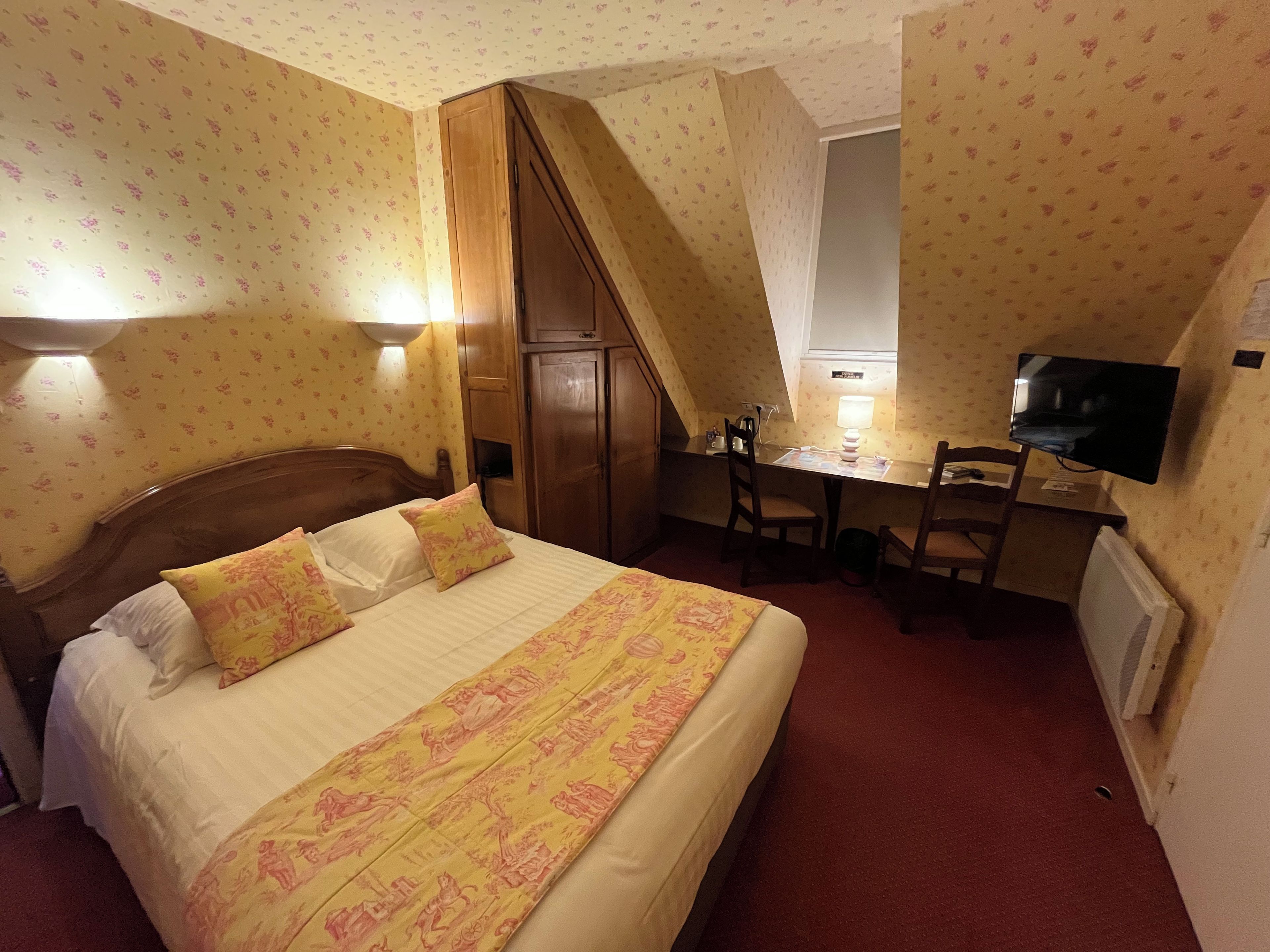 A hotel room with a bed, desk, chair, and television.