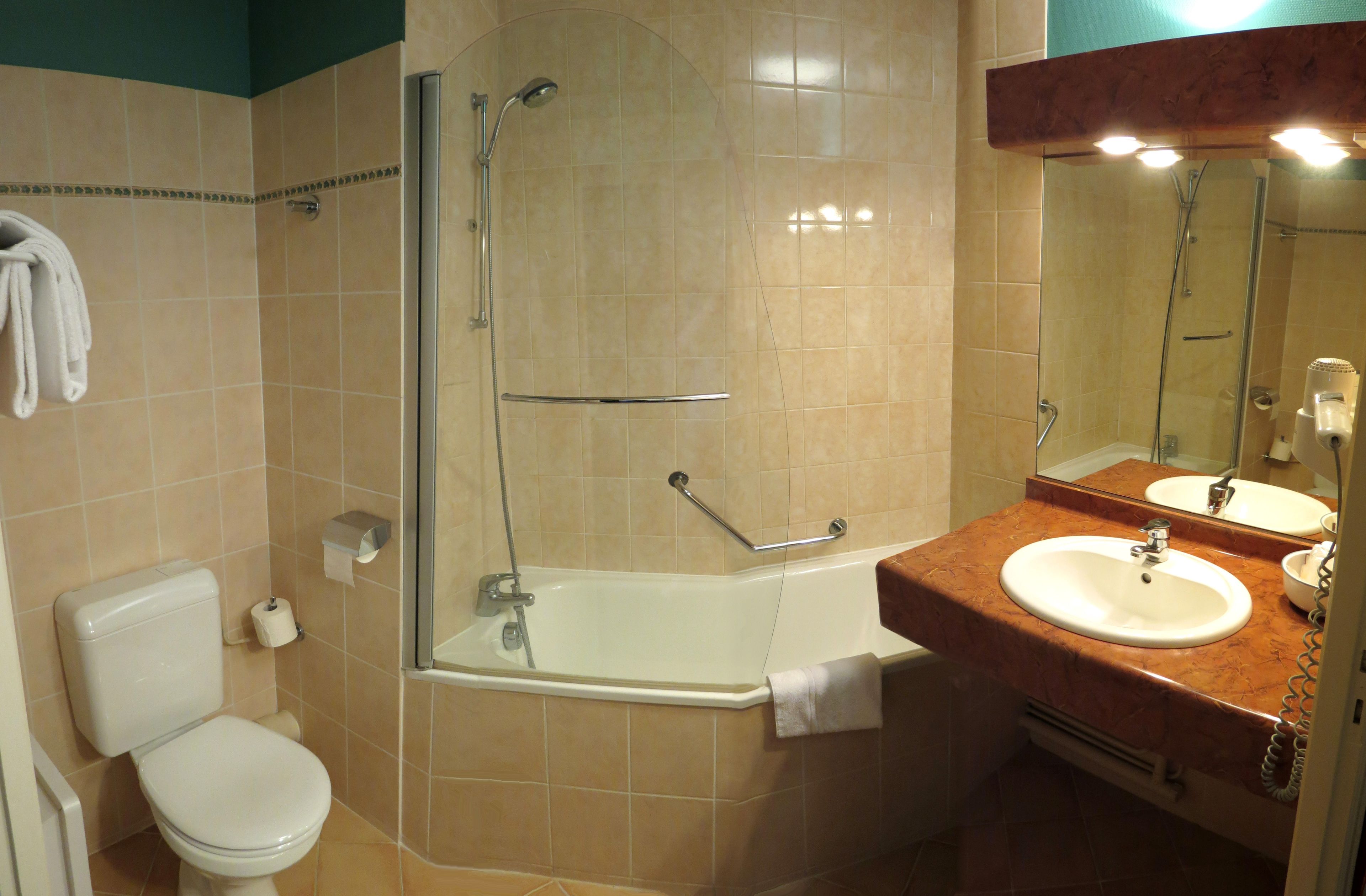 A bathroom with a toilet, a shower, a sink, and a mirror.