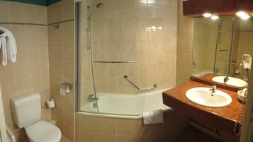 A bathroom with a toilet, a shower, a sink, and a mirror.