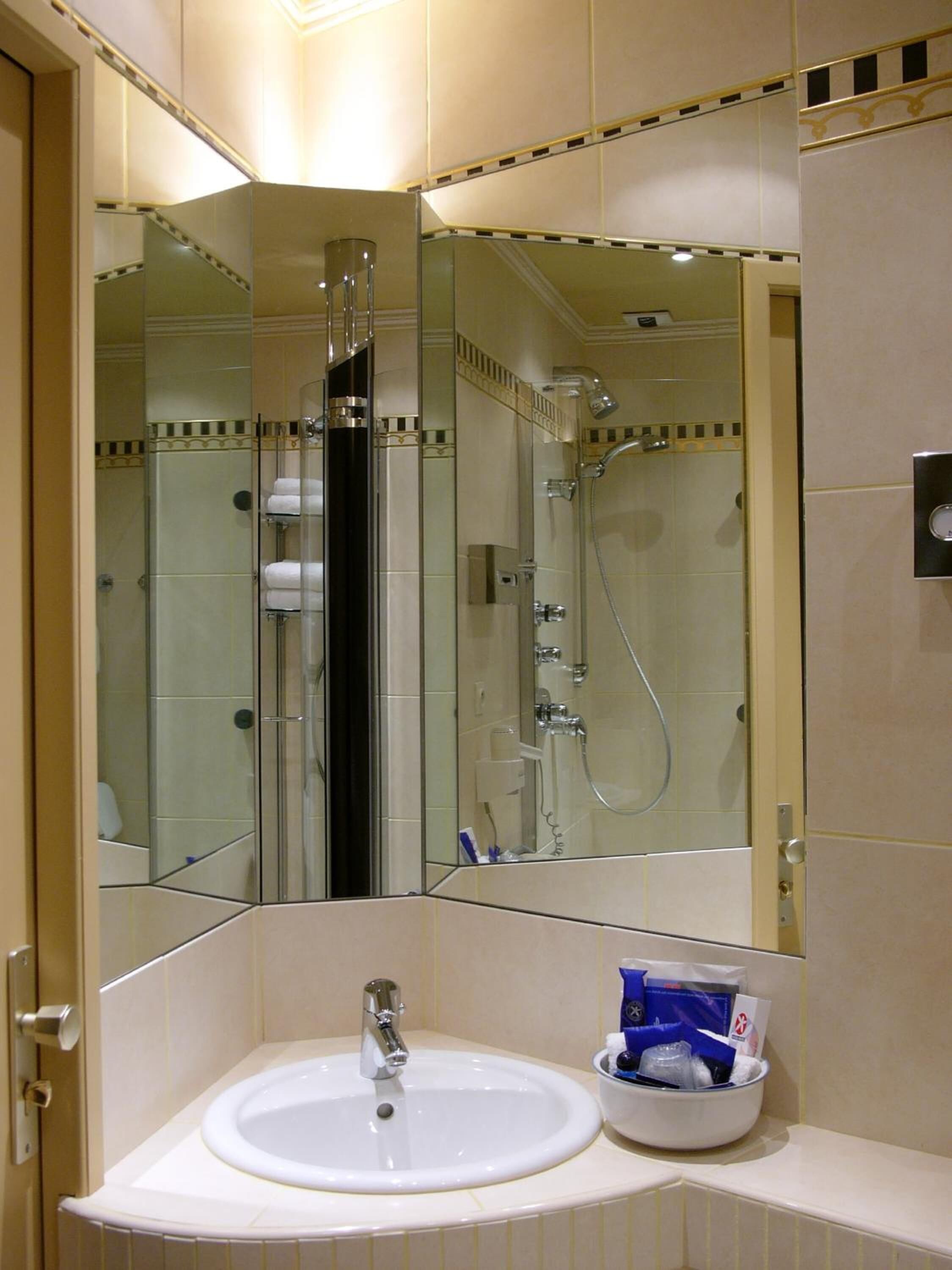 Un baño con lavamanos, espejo y ducha.