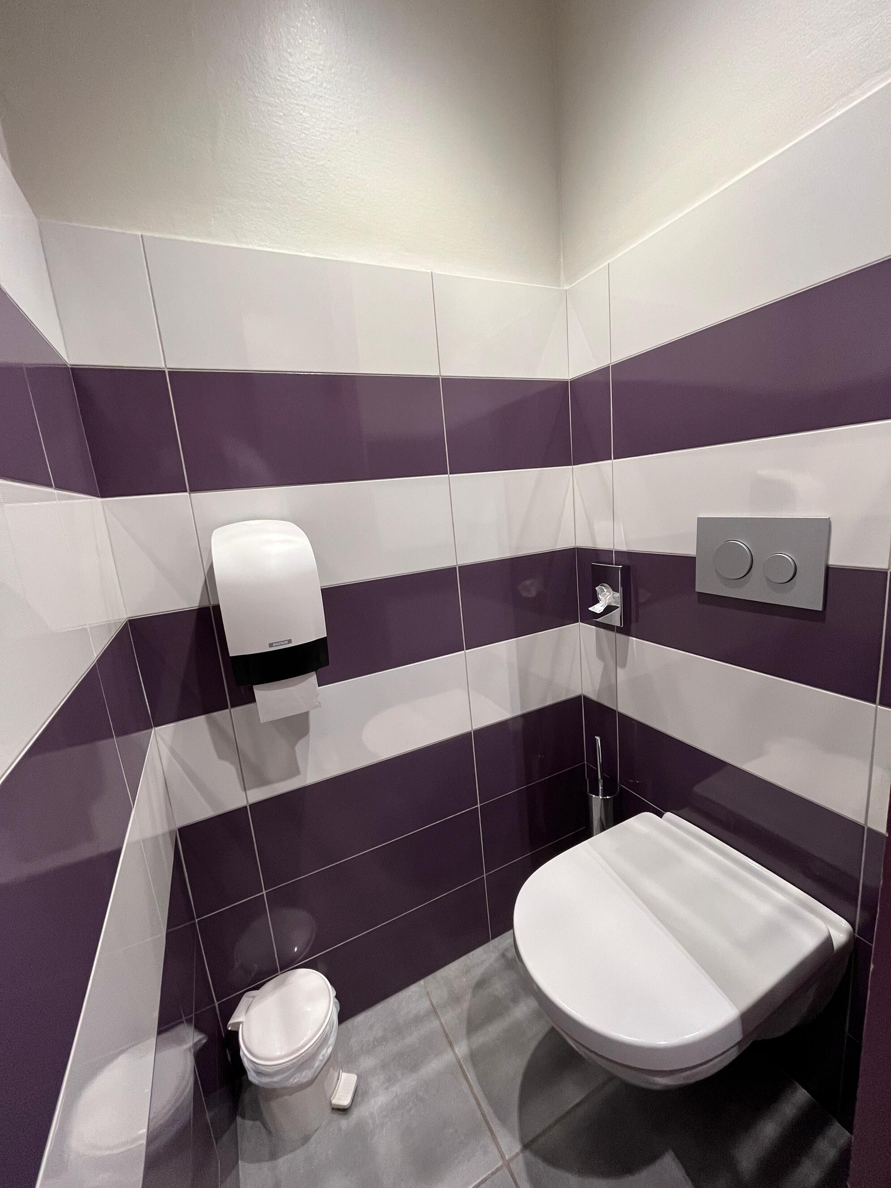 A modern bathroom with a toilet, bidet, and hand dryer.
