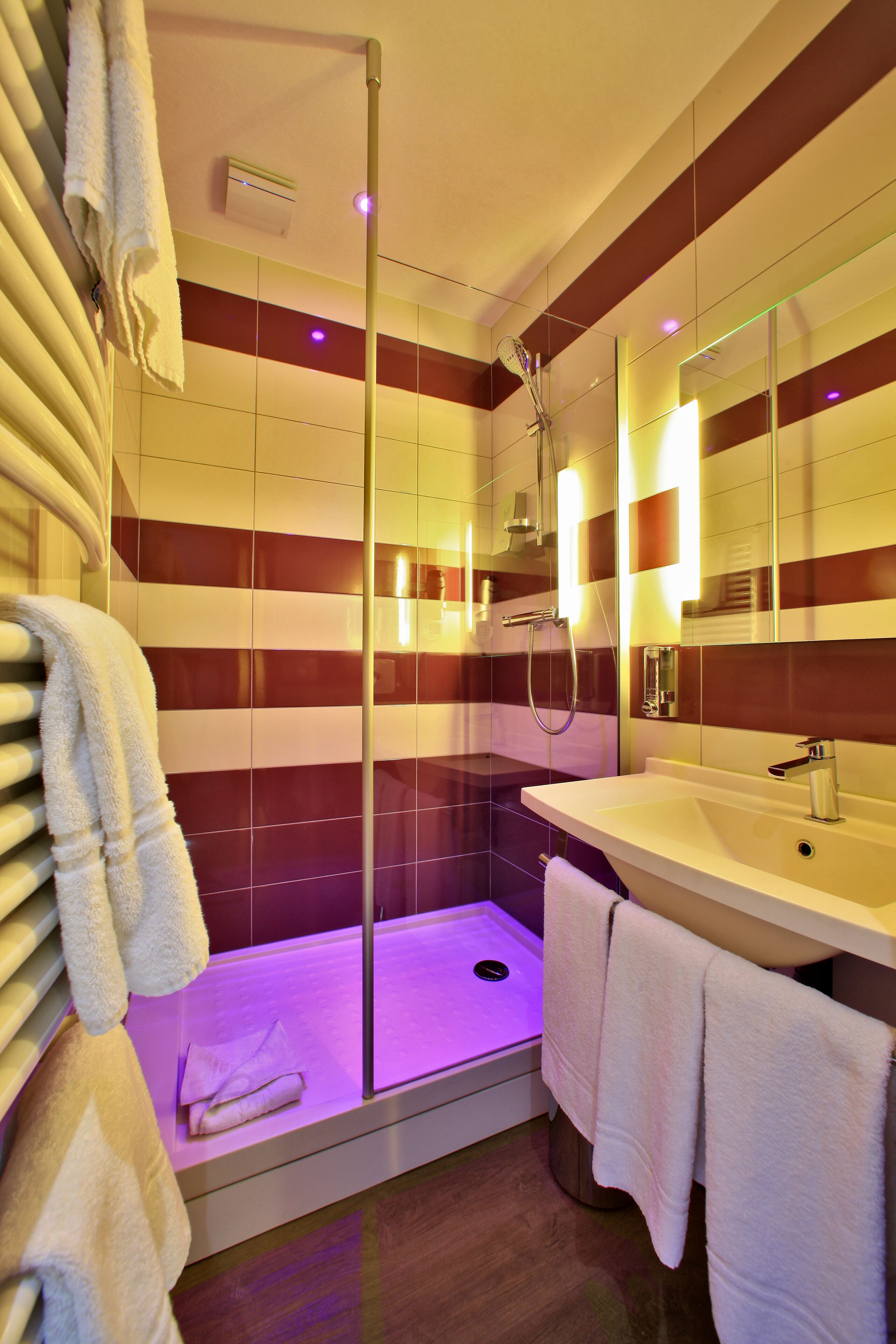 A modern bathroom with a glass-enclosed shower, a white sink, and striped walls.
