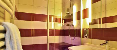 A modern bathroom with a glass-enclosed shower, a white sink, and striped walls.