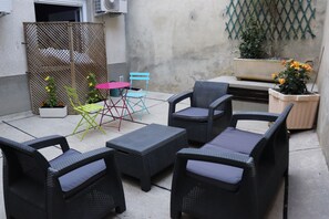 An outdoor patio area with wicker furniture, a small table, and chairs.