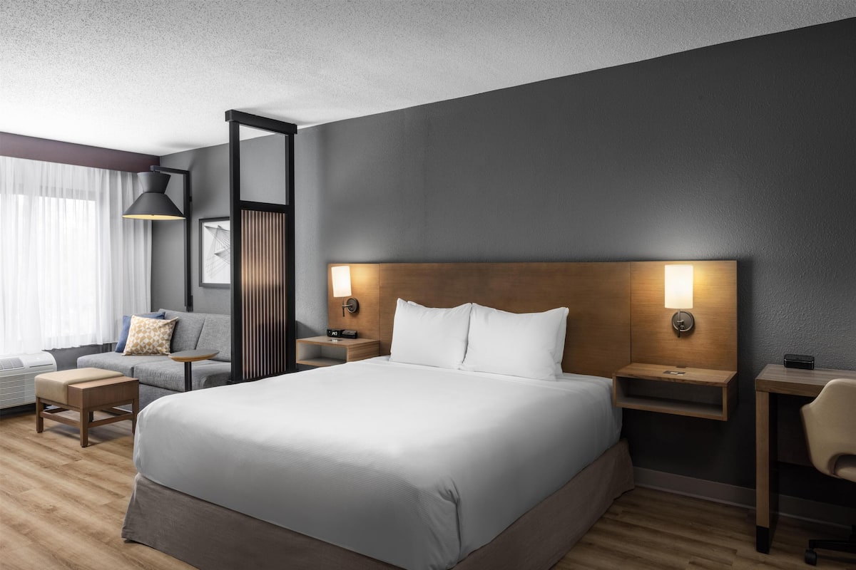 Ein modernes Hotelzimmer mit einem großen Bett, Nachttischen, einem Schreibtisch und einem Stuhl.