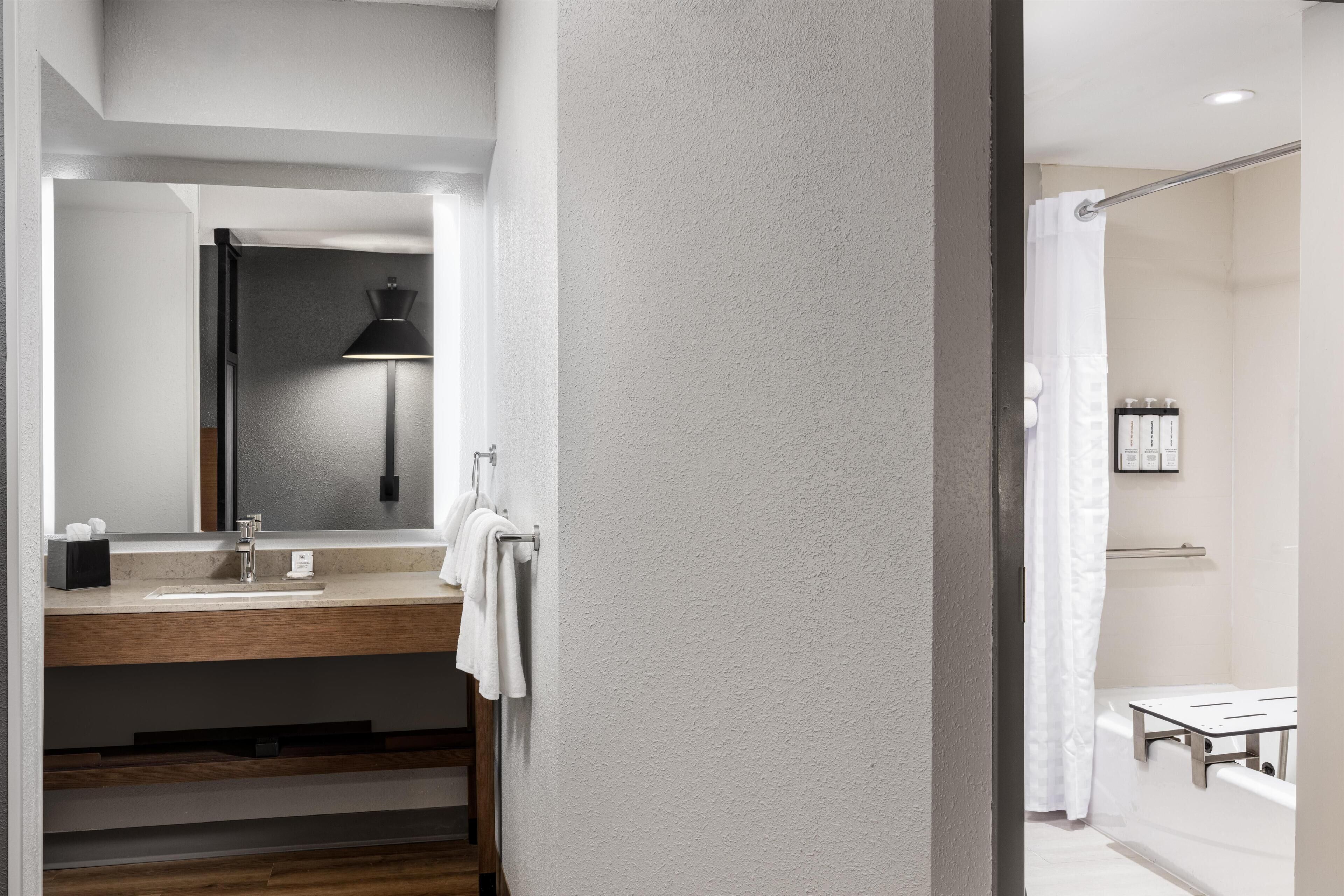A modern bathroom with a sink, mirror, towel rack, and shower area.