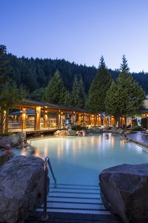 Ein beheizter Poolbereich im Freien mit Holzkonstruktionen und großen Steinen.