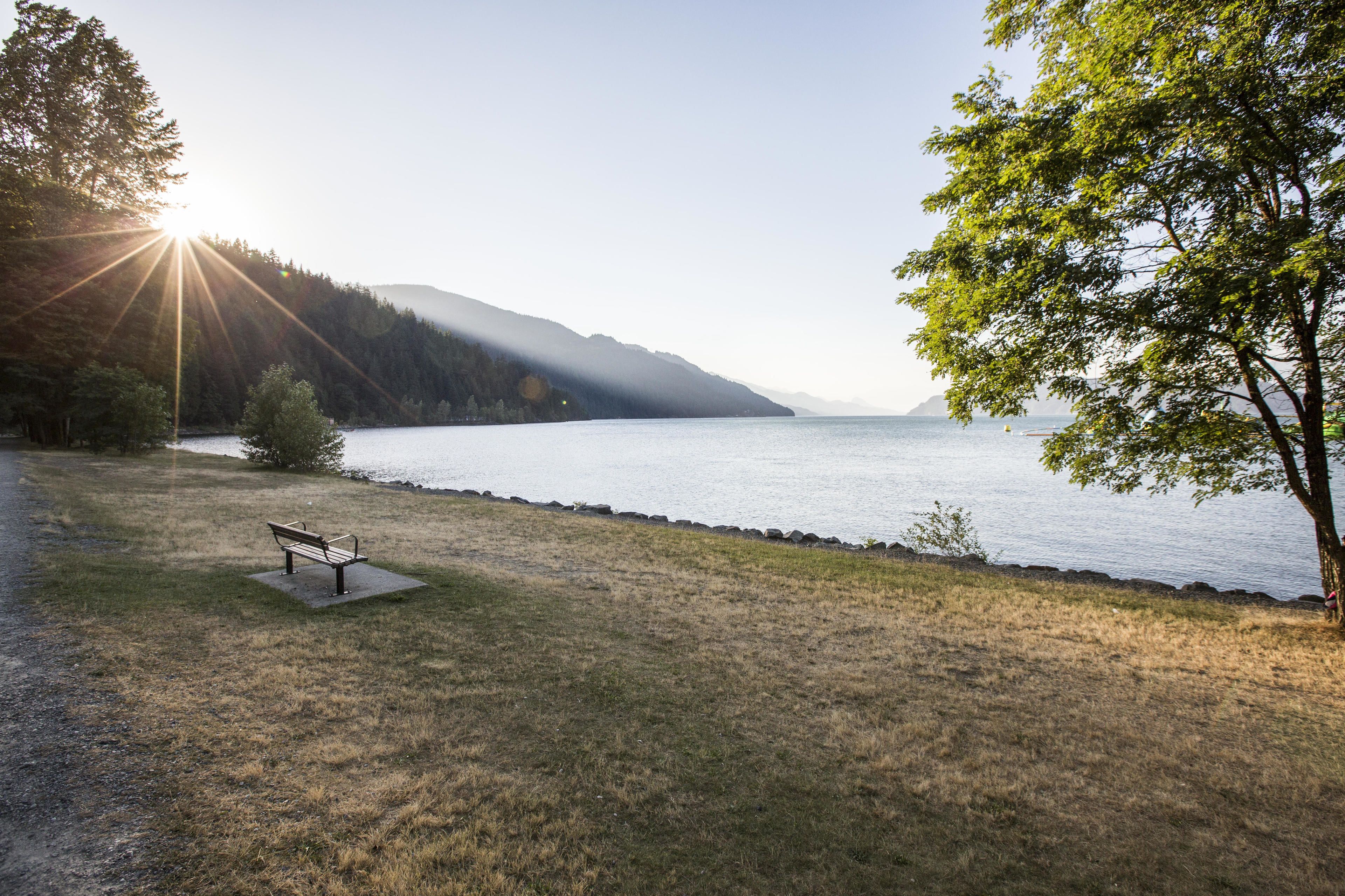 A bench by a lake with a view of the water and hills in the background.